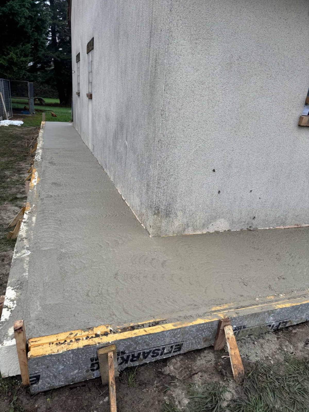 Dalle béton coulée et talochée à l’angle de la maison
