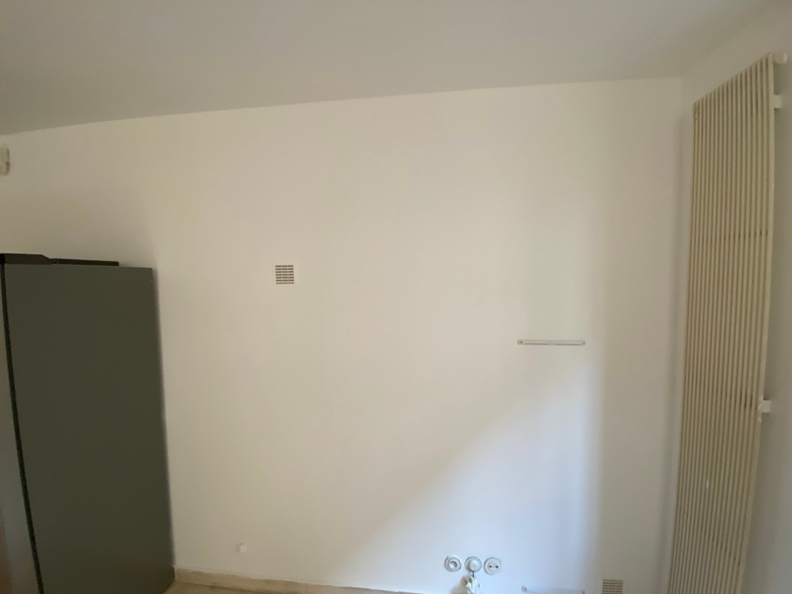 Mur repeint avec grille d’aération et radiateur