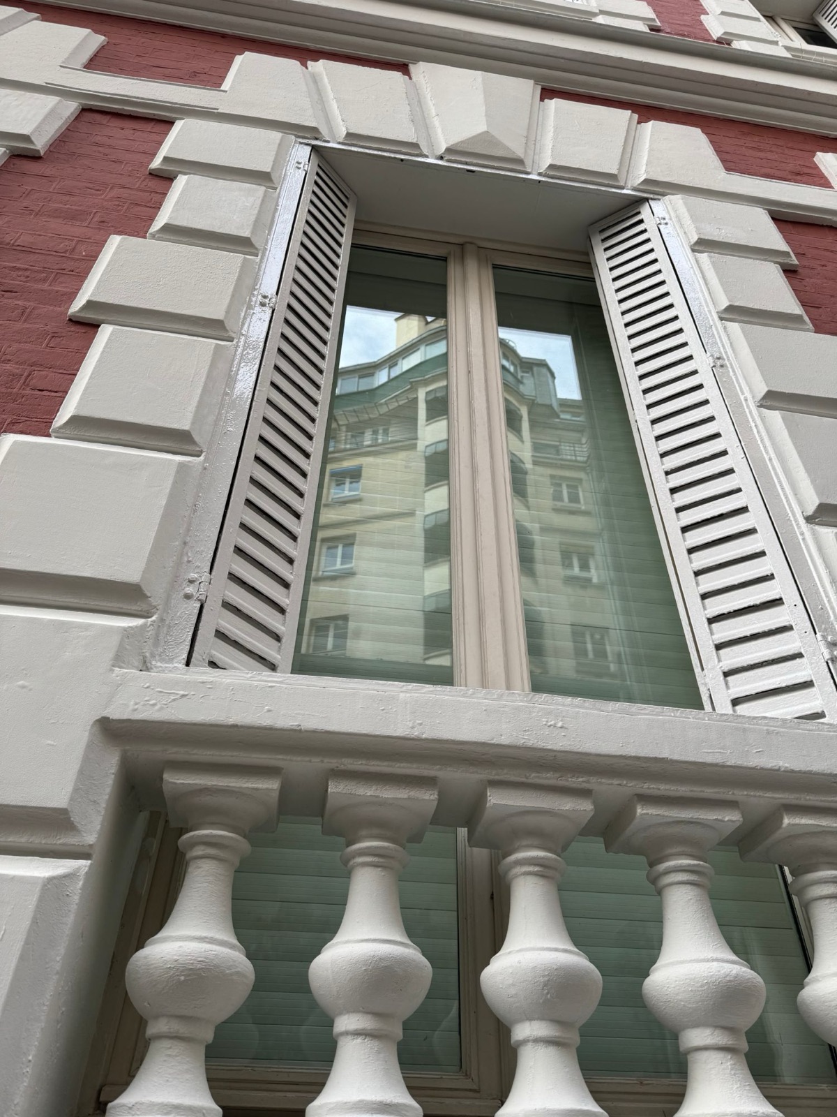 Détail d’une fenêtre avec volets et balustres repeints