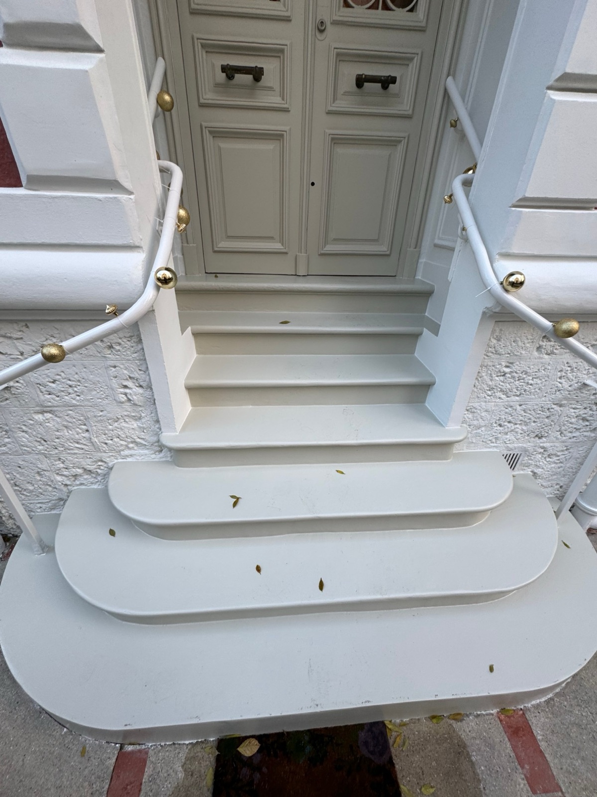 Perron d’entrée repeint en blanc, rampes et boules dorées